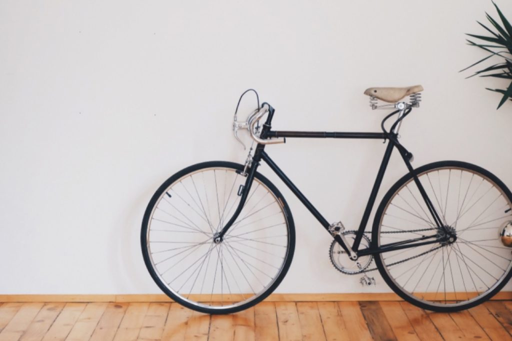 Vélo de ville noir posé contre un mur blanc
