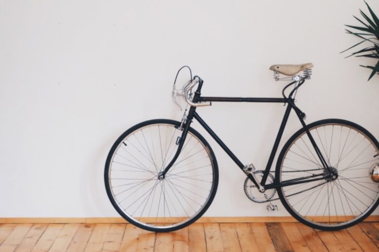 Vélo de ville noir posé contre un mur blanc