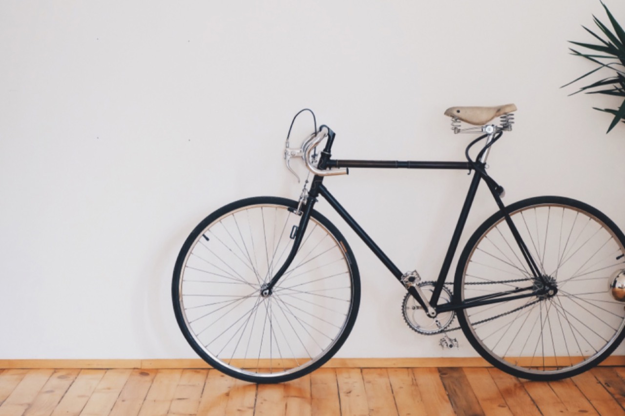 Vélo de ville noir posé contre un mur blanc