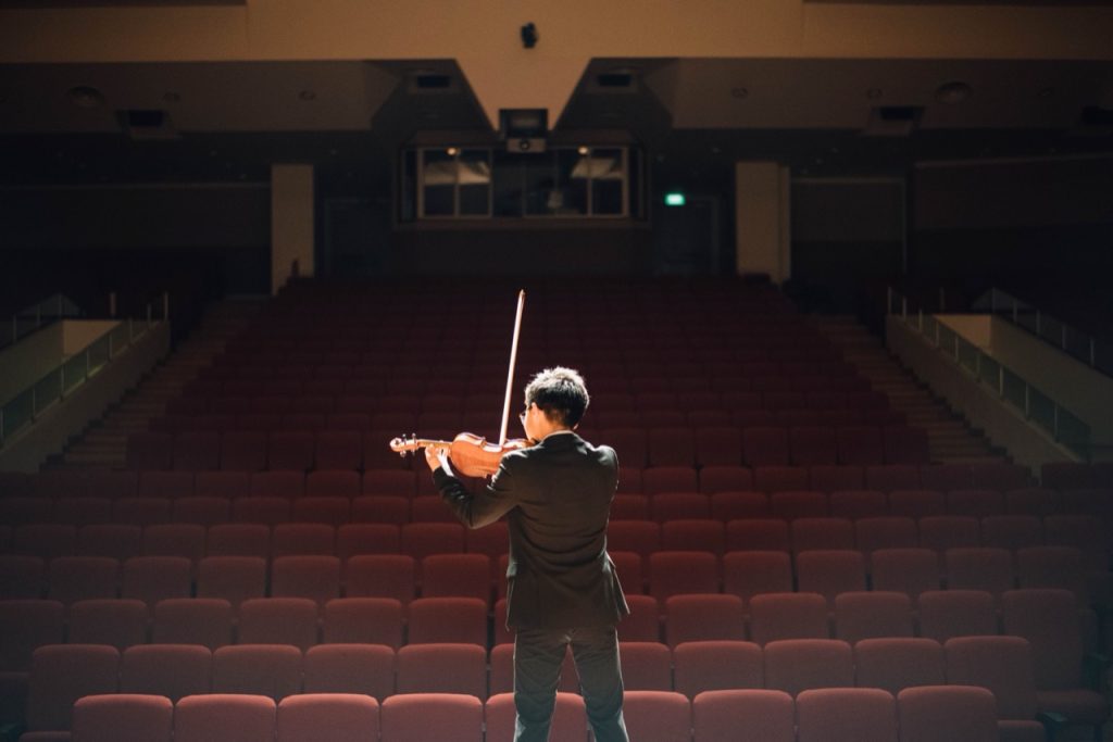 Violoniste de dos face à une salle de concert