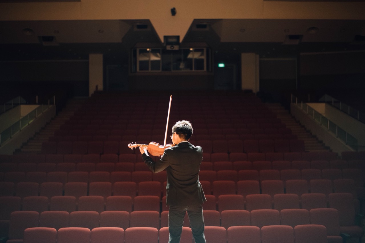 Violoniste de dos face à une salle de concert